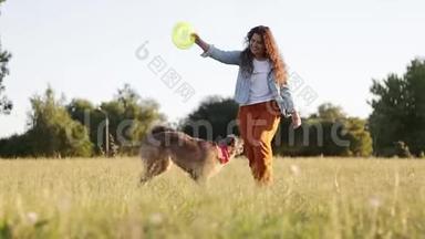 快乐的年轻白种人有着长长的卷发的女人正在和她的狗玩。